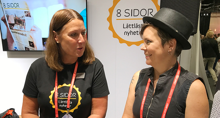 Två kvinnor sitter bredvid varandra. De tittar på varandra och ler.