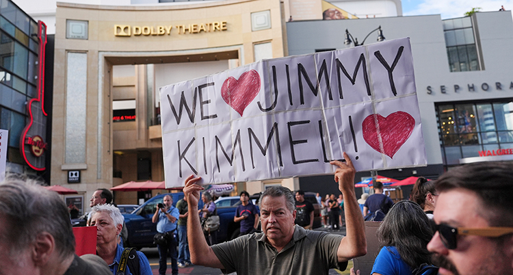 En man håller i en skylt. Vi hjärta Jimmy Kimmel står det på den.