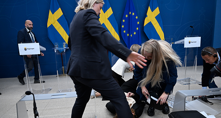 Två kvinnor hjälper hon som har svimmat och som ligger på golvet.