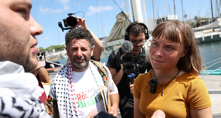 Greta pratar med andra personer vid en hamn.