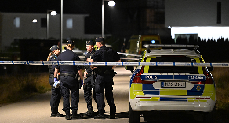 En avspärrad gata. Poliser står innanför avspärrningarna.
