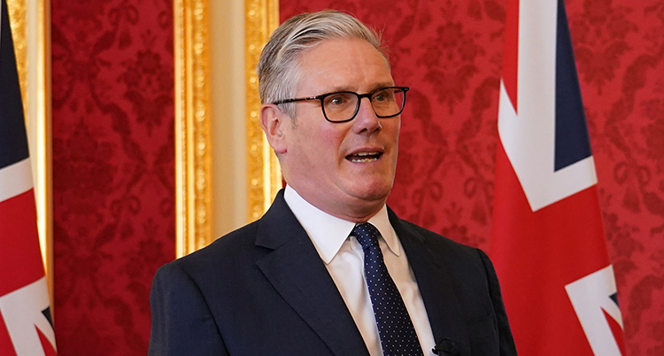 Han pratar. I bakgrunden syns Storbritanniens flagga.
