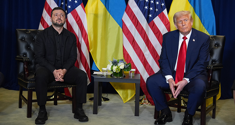 Zelenskyj och Trump sitter på varsin stol bredvid varandra. Bakom dem deras länders flaggor.