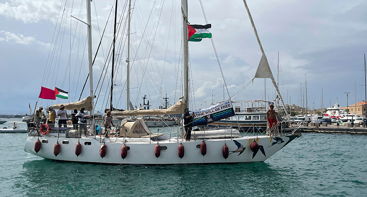 Ungefär tio personer står på båten. Palestinas flagga hänger i masten.