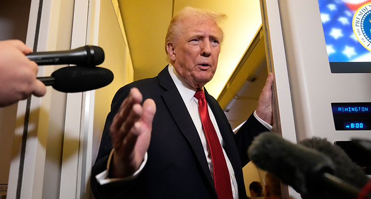 Donald Trump är inne i ett flygplan. Han pratar med journalister som sträcker fram sina mikrofoner.