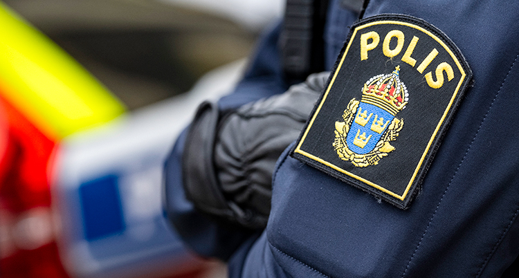 Närbild på en polis som lägger armarna i kors.