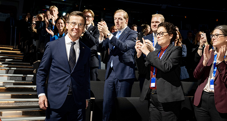 Ulf Kristersson går nerför en trappa. Folk står och applåderar.