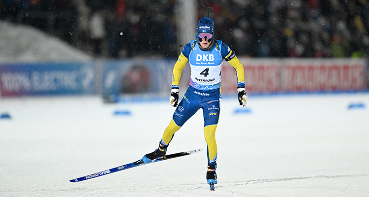 Han åker skidor med ett gevär på ryggen.