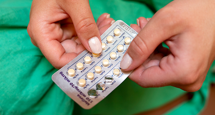 Närbild på två händer som håller i en karta med piller.