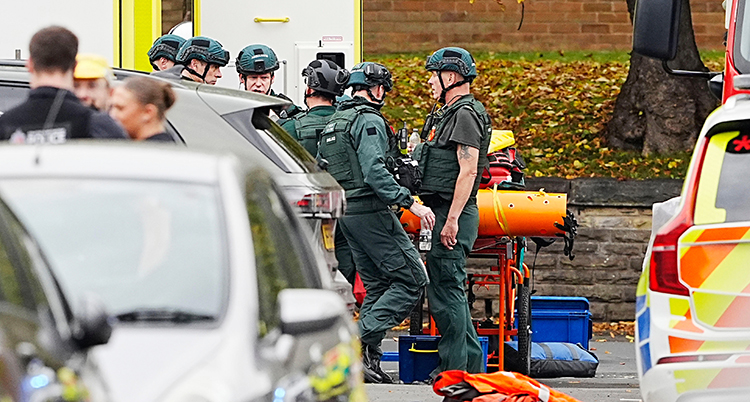 Flera personer vid en ambulans och en polisbil.