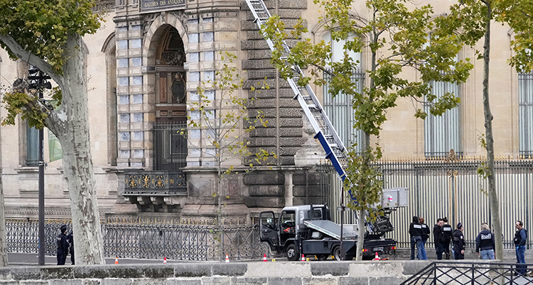 En bil med stege står utanför en stor byggnad.
