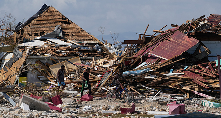 Folk står vid förstörda hus.