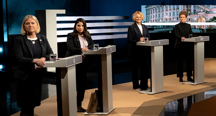 De står vid små bord i en tv-studio.