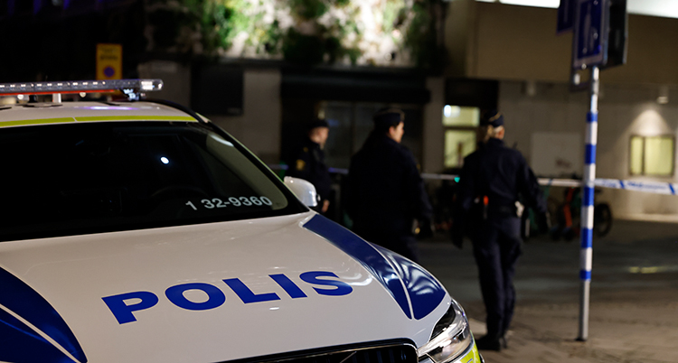 En polisbil och flera poliser syns. Det är kväll.