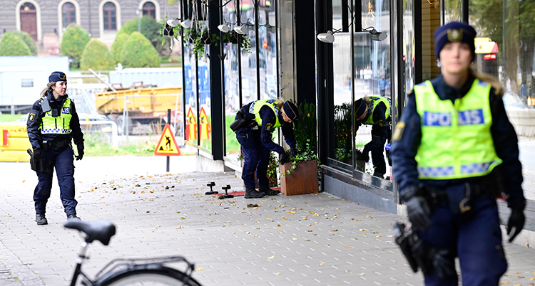 Några poliser undersöker saker på en gågata.