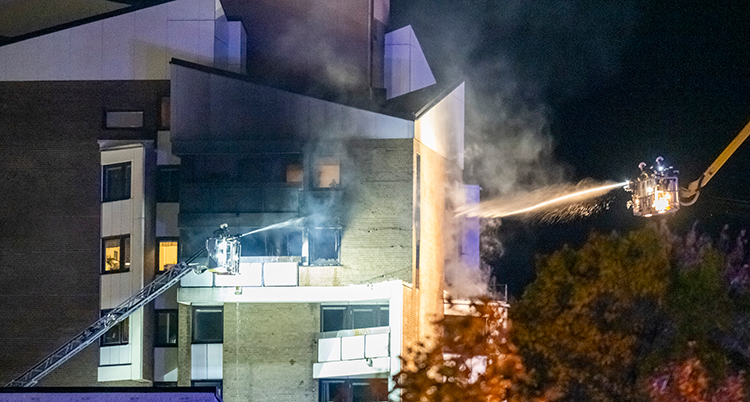 Brandmännen från två olika brandbilar sprutar vatten på huset.