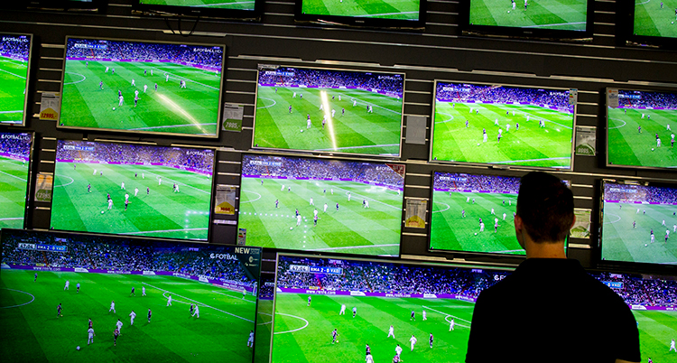 En man står framför flera tv-skärmar.