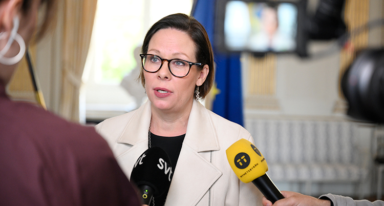 Hon står och blir intervjuad av flera journalister.