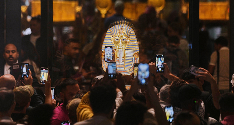 Människor står och tar bilder på en gyllene mask.