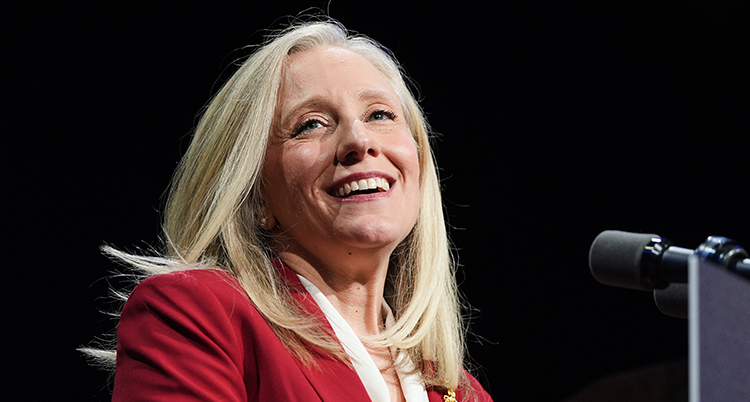 Hon har blont hår. Hon ler.