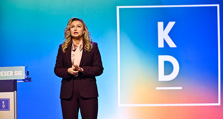 Hon står på en scen och pratar.