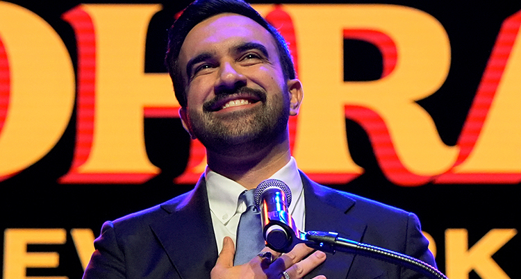 Han ler och har en mikrofon framför sig.