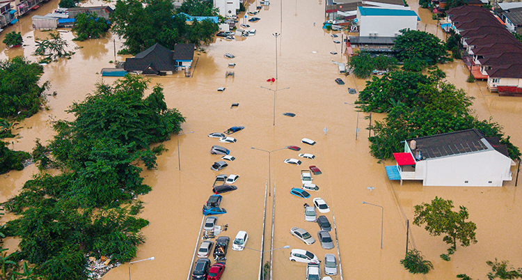 Bild tagen från luften. Tak på många bilar och hus syns. Vattnet är brunt.