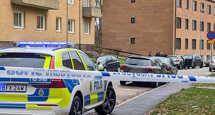 Poliser på en gata framför hus med lägenheter.