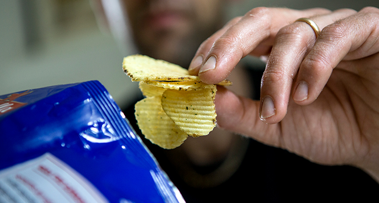 En hand håller i chips.
