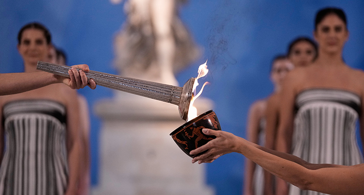 En fackla hålls mot en skål med eld.