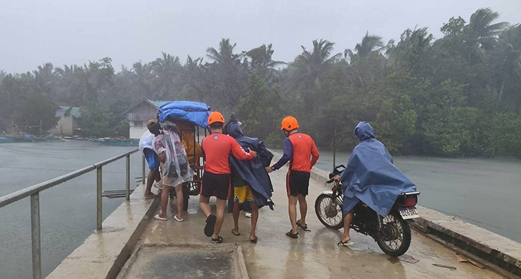 Människor i regnkläder vid en brygga.