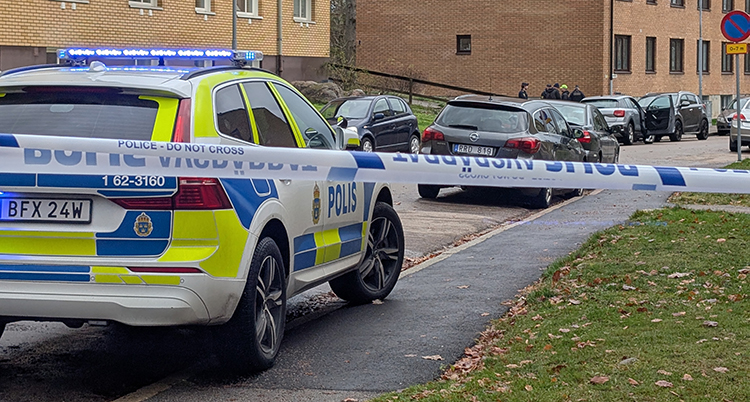 Poliser på en gata framför hus med lägenheter.