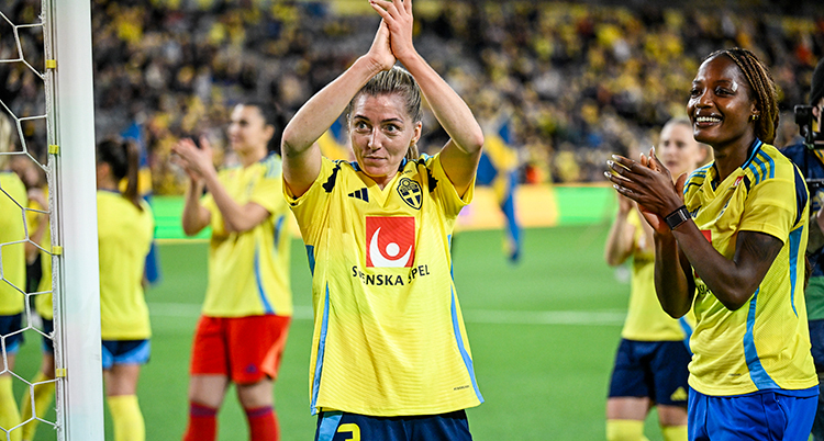 Hon har landslagets tröja. Hon klappar händerna ovanför huvudet.