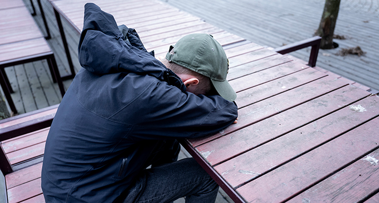 En ung kille har ansiktet mot ett bord.