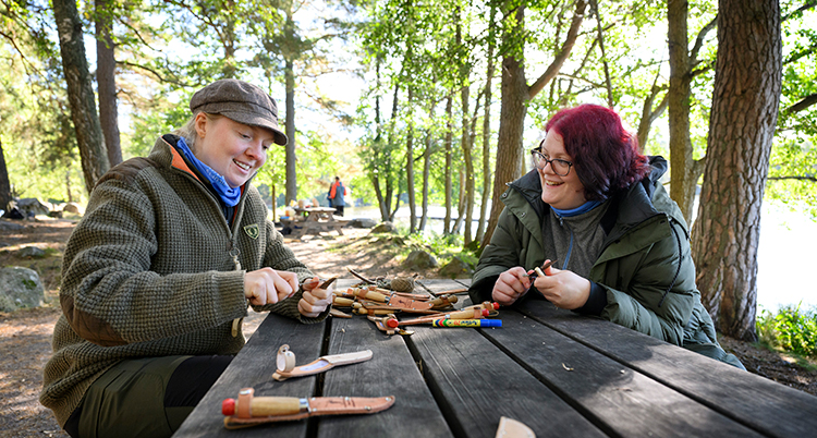 De sitter mitt emot varandra vid ett bord i en skog.