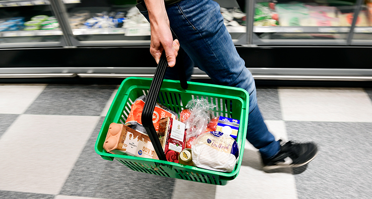 An man bär på en korg med mat i en affär.