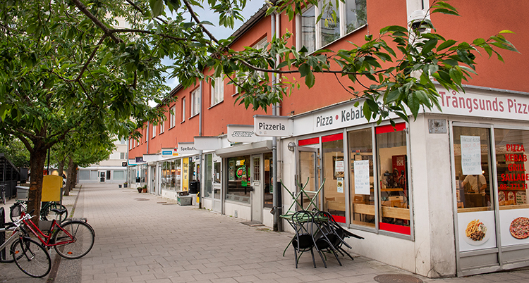 Ett hus med butiker och restauranger. På gatan finns ett bord och cyklar.