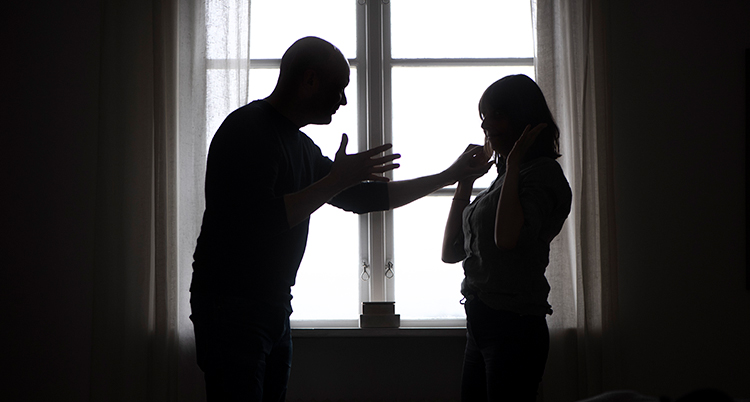 En man lyfter handen mot en kvinna.