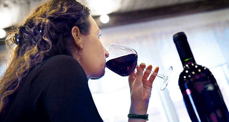 En kvinna som dricker ett glas rött vin.