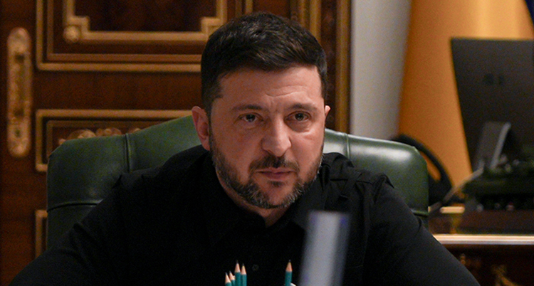 Han sitter vid ett skrivbord. Han är allvarlig.