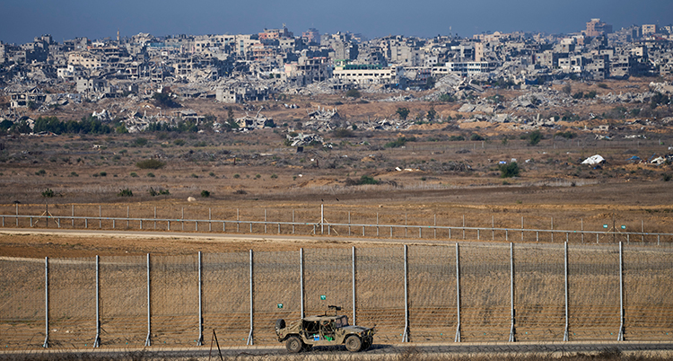 Längst bort syns staden. Sedan kommer ett fält, efter det ett staket. Israels militärer är vid staketet.