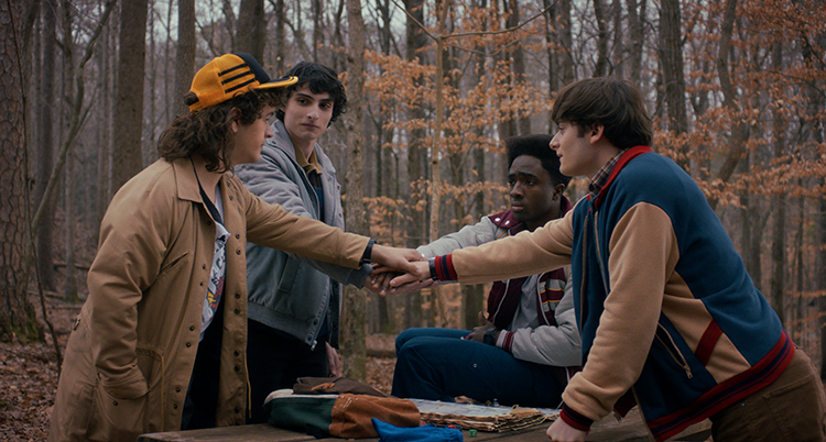 De står runt varandra. De har sträckt ut sina händer som möts i mitten.