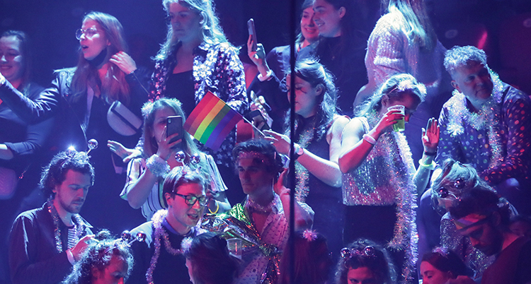 De viftar med flaggor i regnbågens färger, Prides flagga.