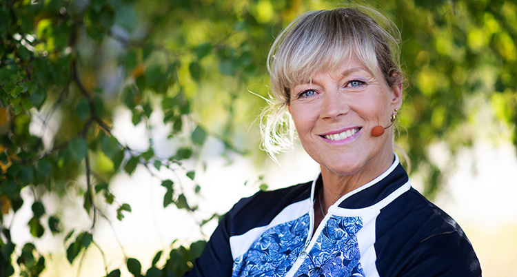 Hon ser glad ut och tittar in i kameran. Hon har en mikrofon vid munnen.