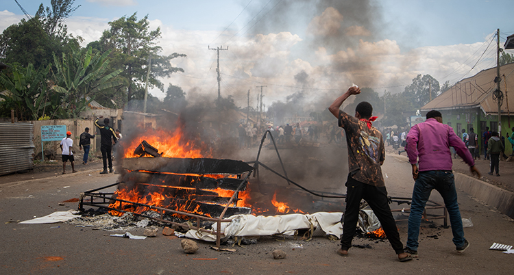 Två män står bredvid en eld på gatan.