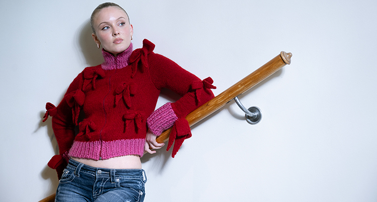 Hon står mot en vägg mot en ledstång.