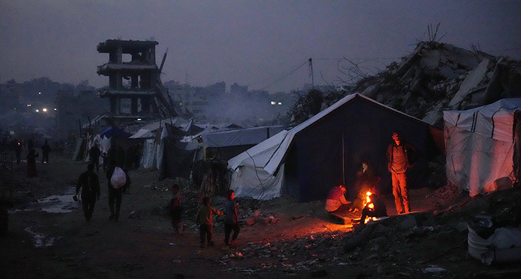 Det är mörkt. Några barn leker vid en eld utanför ett tält.