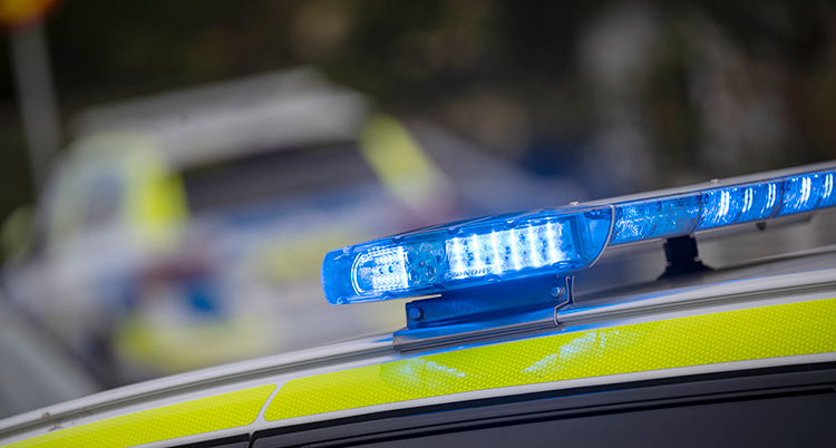 En närbild på lamporna på taket av en polisbil. Längre bort står en till polisbil.