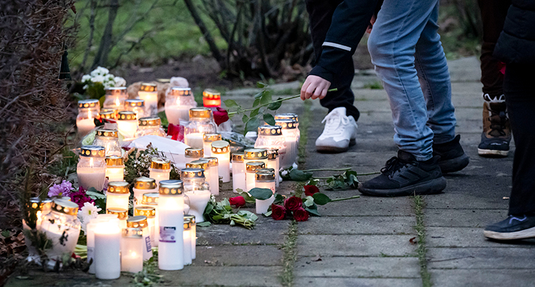 Det ligger massor av ljuslyktor och blommor på marken.