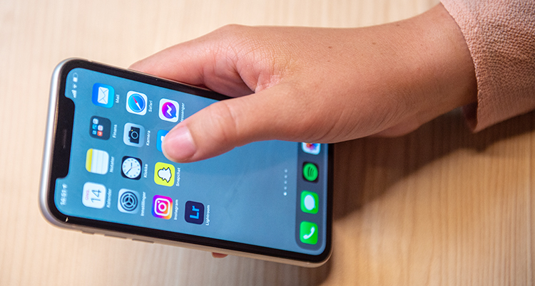 En närbild på en hand som håller i en mobiltelefon med olika appar.